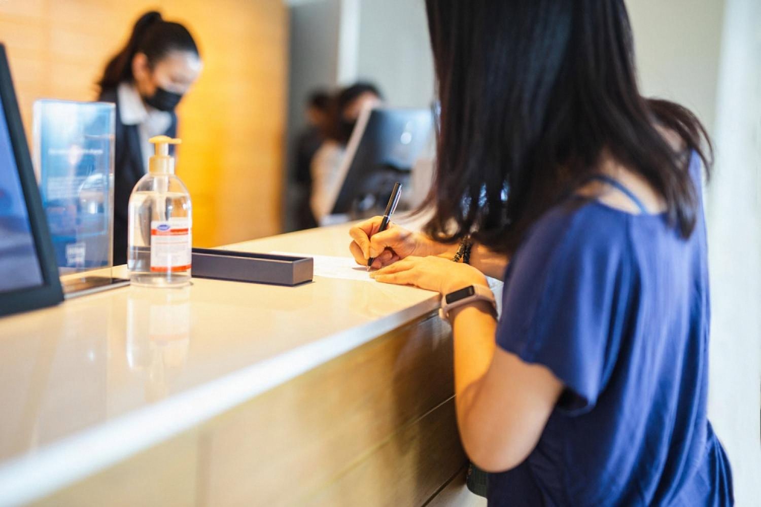 Guest filling in a paper registration form at a traditional hotel front desk